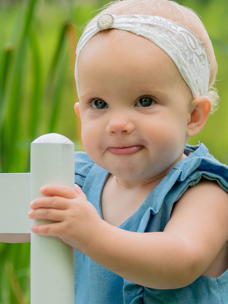 one year old standing up holding on to a white rocking chair. child milestones